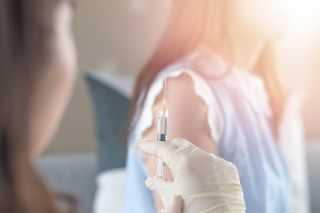 A medical professional prepares to administer a vaccine.